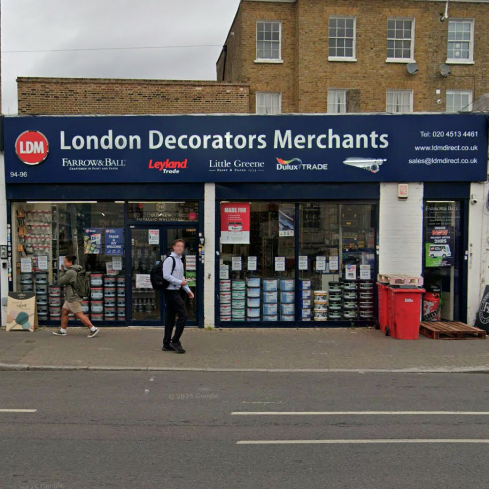 Storefront of London Decorators Merchants in Brixton with people walking by on Acre Lane.
