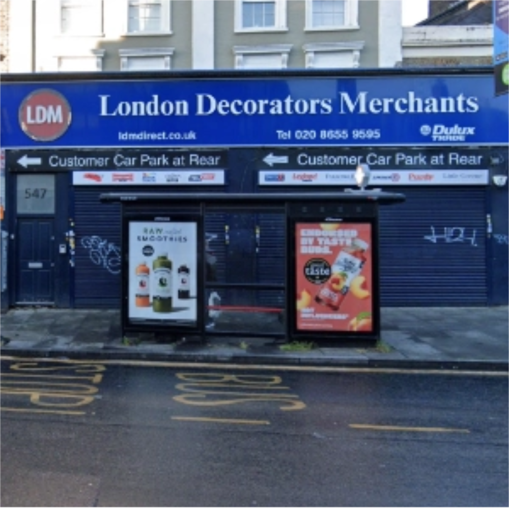 Shopfront of London Decorators Merchants Norwood Store with advertising posters on a bus stop  bench in front of the store entrance.